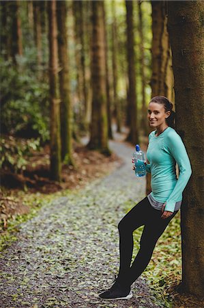 simsearch:6109-08536382,k - Fit brunette taking a break and holding bottle against a tree in the woods Photographie de stock - Premium Libres de Droits, Code: 6109-08435614