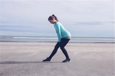 simsearch:6109-08435603,k - Beautiful brunette stretching her legs at the beach Stock Photo - Premium Royalty-Free, Code: 6109-08435622