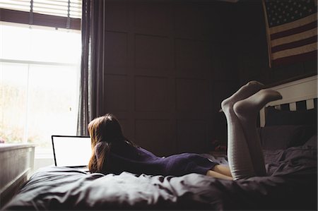 flat - Brunette using laptop lying on the bed at home Stock Photo - Premium Royalty-Free, Code: 6109-08435637
