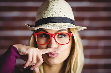 Blonde woman having a fake mustache on brick wall Stock Photo - Premium Royalty-Free, Code: 6109-08435772