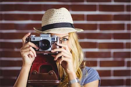 Blonde woman taking picture on brick wall Stock Photo - Premium Royalty-Free, Code: 6109-08435782