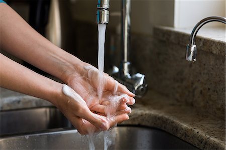 simsearch:6109-08489043,k - Pretty woman washing her hands in the kitchen Stock Photo - Premium Royalty-Free, Code: 6109-08435703