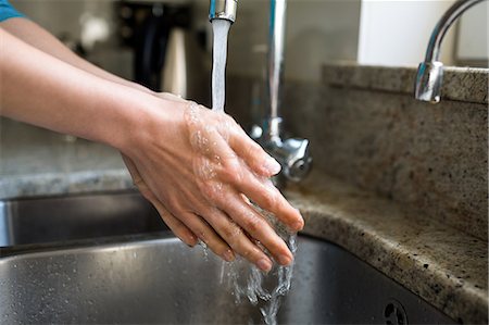 simsearch:6109-08489043,k - Pretty woman washing her hands in the kitchen Photographie de stock - Premium Libres de Droits, Code: 6109-08435702