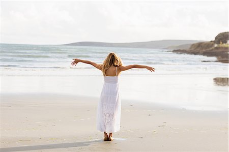 Beautiful blonde woman relaxing with arms outstretched in the coastline Fotografie stock - Premium Royalty-Free, Codice: 6109-08435735