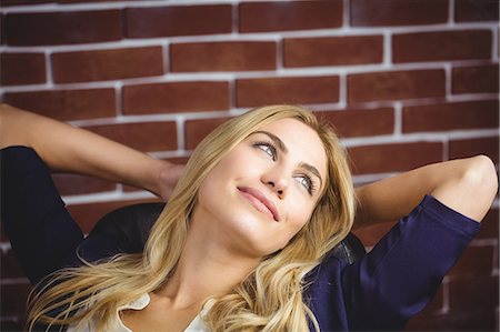 posieren - Blonde woman relaxing in chair on brick wall Stockbilder - Premium RF Lizenzfrei, Bildnummer: 6109-08435820