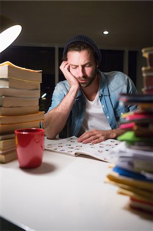 simsearch:6109-08581488,k - Hipster reading a document with stacks of books Stock Photo - Premium Royalty-Free, Code: 6109-08581445