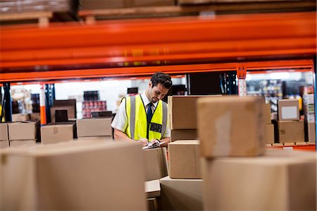 Warehouse manager writing on his clipboard Foto de stock - Sin royalties Premium, Código: 6109-08581543