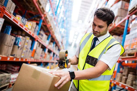 person taping a box - Manager with yellow coat preparing a shipment Stock Photo - Premium Royalty-Free, Code: 6109-08581533