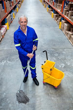 floor cleaning - Smiling man moping warehouse floor Stock Photo - Premium Royalty-Free, Code: 6109-08581694