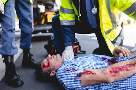 simsearch:6109-08689784,k - Ambulanceman healing injured man Photographie de stock - Premium Libres de Droits, Code: 6109-08581773