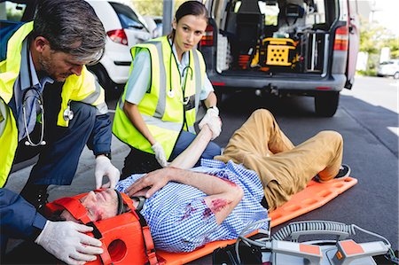 simsearch:6109-08689784,k - Ambulancemen healing injured man Photographie de stock - Premium Libres de Droits, Code: 6109-08581783