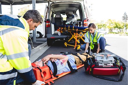 simsearch:6109-08581847,k - Ambulancemen healing injured man Photographie de stock - Premium Libres de Droits, Code: 6109-08581789