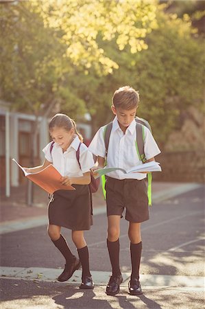 enseigner - School kids reading books while walking in campus Photographie de stock - Premium Libres de Droits, Code: 6109-08581956