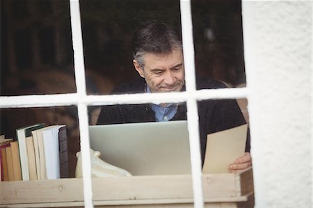 simsearch:6109-08582007,k - Mature man working at desk with laptop and documents Fotografie stock - Premium Royalty-Free, Codice: 6109-08581975