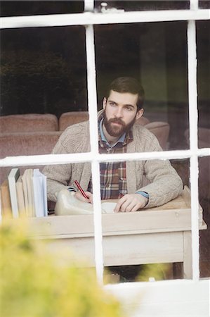simsearch:6109-08582007,k - Handsome hipster man looking through window while writing Fotografie stock - Premium Royalty-Free, Codice: 6109-08581987