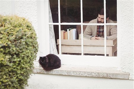 Facing view of hipster man working at desk at window Foto de stock - Sin royalties Premium, Código: 6109-08581991