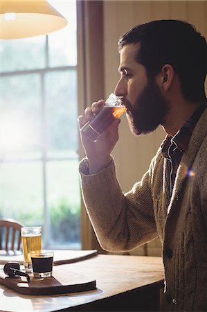 Profile view of hipster man drinking a shot Stock Photo - Premium Royalty-Free, Code: 6109-08582063