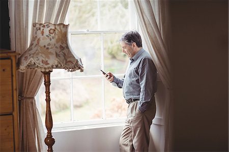 simsearch:6109-08700206,k - Mature man using mobile phone at window Stock Photo - Premium Royalty-Free, Code: 6109-08582029