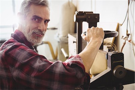 Cobbler looking at camera and using a machine Stock Photo - Premium Royalty-Free, Code: 6109-08582139