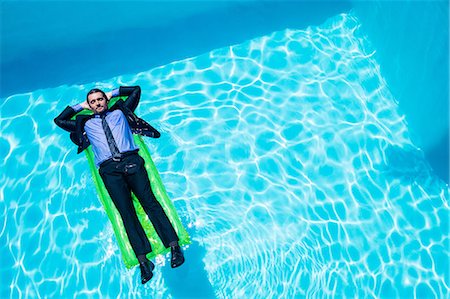 stylish swimming pool - Businessman relaxing on inflatable Stock Photo - Premium Royalty-Free, Code: 6109-08536453