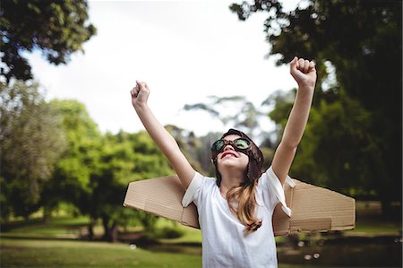 simsearch:6109-08536415,k - Happy girl standing in park with hands raised Foto de stock - Sin royalties Premium, Código: 6109-08536437