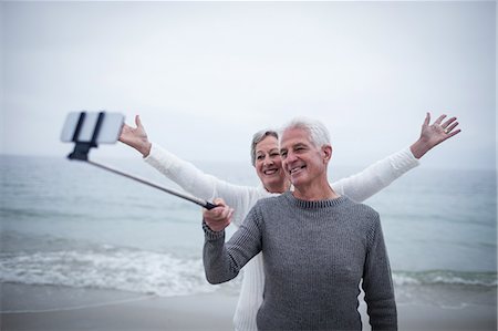 suéters - Senior couple taking a selfie on the beach Foto de stock - Sin royalties Premium, Código: 6109-08536506