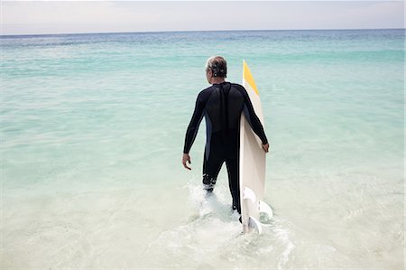 simsearch:6109-08536508,k - Senior man walking towards sea with a surfboard Stock Photo - Premium Royalty-Free, Code: 6109-08536510