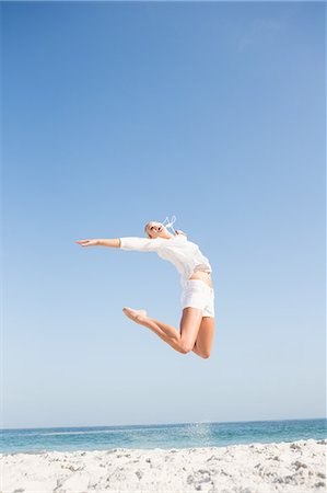 simsearch:6109-08536732,k - Blonde woman jumping on the beach Fotografie stock - Premium Royalty-Free, Codice: 6109-08536729