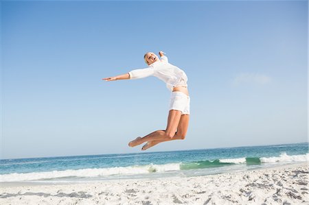 simsearch:6109-08536732,k - Blonde woman jumping on the beach Fotografie stock - Premium Royalty-Free, Codice: 6109-08536732