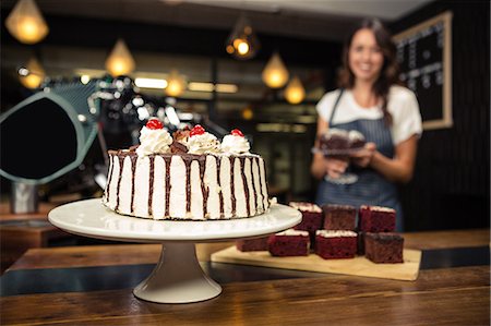 Smiling barista holding plate with cake Photographie de stock - Premium Libres de Droits, Code: 6109-08536936