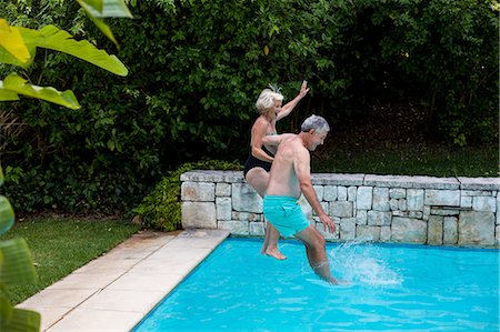 swimwear - Senior couple jumping in swimming pool at yard Foto de stock - Sin royalties Premium, Código: 6109-08537046