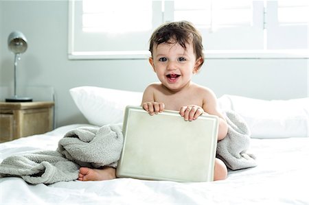 simsearch:6109-08390051,k - Happy cute baby boy holding tablet PC on bed Foto de stock - Sin royalties Premium, Código: 6109-08537051