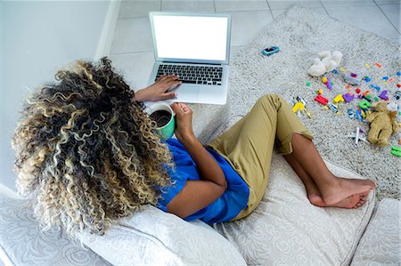 simsearch:6109-08804908,k - Young woman using laptop while having coffee in living room Photographie de stock - Premium Libres de Droits, Code: 6109-08537161