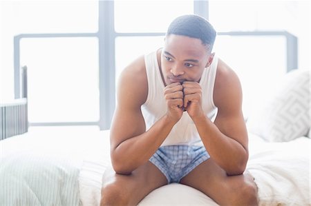 simsearch:6109-08537404,k - Tensed young man sitting on bed Stock Photo - Premium Royalty-Free, Code: 6109-08537116