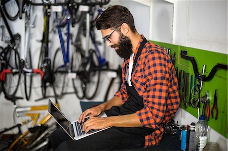 simsearch:6109-08537278,k - Bike mechanic checking laptop Stock Photo - Premium Royalty-Free, Code: 6109-08537218