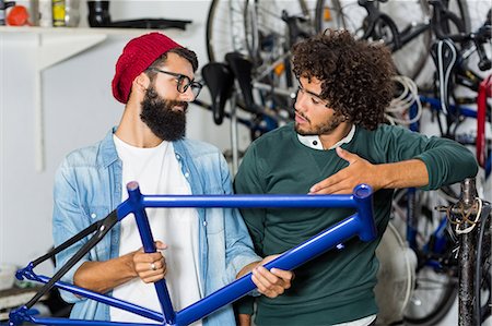 Hipster bike mechanic holding a bike piece Fotografie stock - Premium Royalty-Free, Codice: 6109-08537300