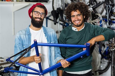 simsearch:6109-08537274,k - Hipster bike mechanic holding a bike piece Stock Photo - Premium Royalty-Free, Code: 6109-08537301