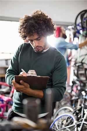 drill - Hipster bike mechanic writing on clipboard Stock Photo - Premium Royalty-Free, Code: 6109-08537305