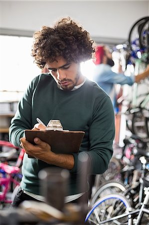 simsearch:6109-08537274,k - Hipster bike mechanic writing on clipboard Stock Photo - Premium Royalty-Free, Code: 6109-08537305