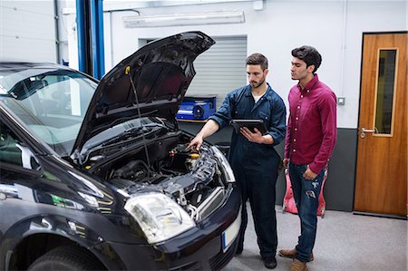 Mechanic showing customer the problem with car using diagnostic tool Stock Photo - Premium Royalty-Free, Code: 6109-08537661