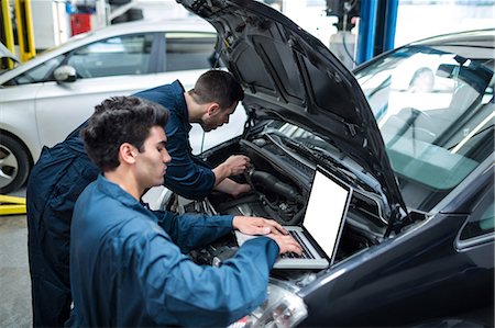 simsearch:6109-08537707,k - Mechanics examining car engine using laptop Foto de stock - Sin royalties Premium, Código: 6109-08537616