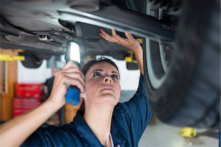 simsearch:6109-08537757,k - Female mechanic examining car using flashlight Foto de stock - Sin royalties Premium, Código: 6109-08537713