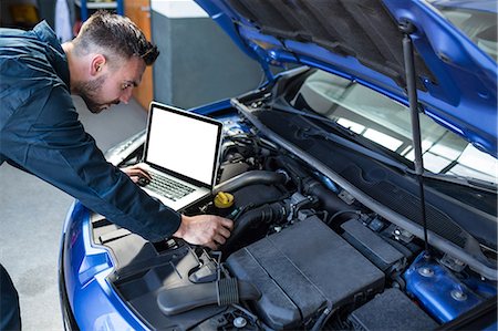 simsearch:6109-08537758,k - Mechanic examining car engine with help of laptop Foto de stock - Sin royalties Premium, Código: 6109-08537716