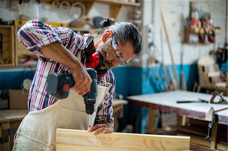 simsearch:6109-08537962,k - Carpenter drilling a hole in a wooden plank Stock Photo - Premium Royalty-Free, Code: 6109-08537940