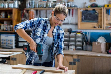 fixing woman - Female carpenter drilling a hole in a wooden plank Stock Photo - Premium Royalty-Free, Code: 6109-08538084