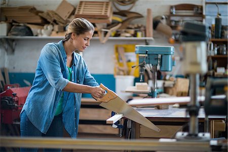 Female carpenter cutting plank with hand saw Stock Photo - Premium Royalty-Free, Code: 6109-08538091