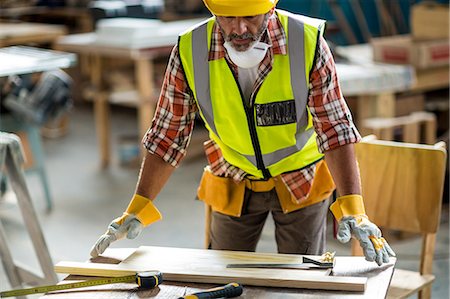 Carpenter measuring wooden plank Photographie de stock - Premium Libres de Droits, Code: 6109-08538159