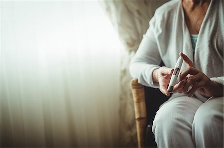 senior woman alone thinking - Senior woman holding a blood glucose monitor Stock Photo - Premium Royalty-Free, Code: 6109-08538189