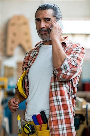 Carpenter talking on mobile phone Stock Photo - Premium Royalty-Free, Code: 6109-08538131