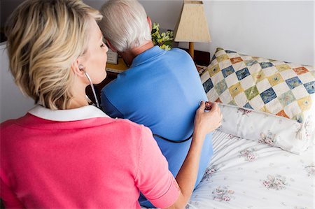 Nurse using stethoscope to take care of a senior man Stock Photo - Premium Royalty-Free, Code: 6109-08538279